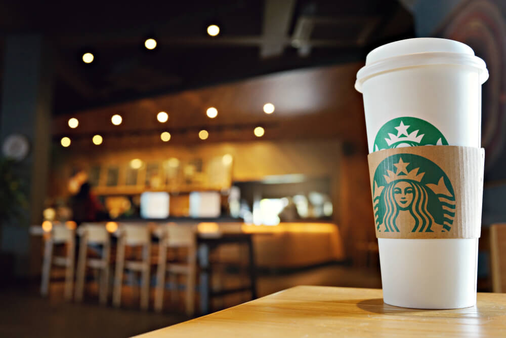 A hot Starbucks drink in front of a table area where people can work